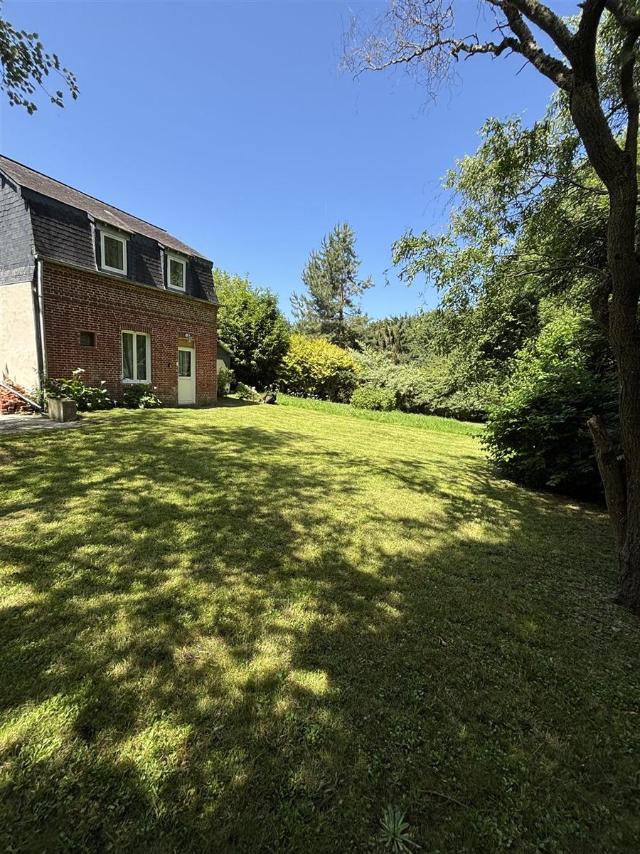 Pelouse tondue autour d'une maison en brique, finitions soignées le long des murs